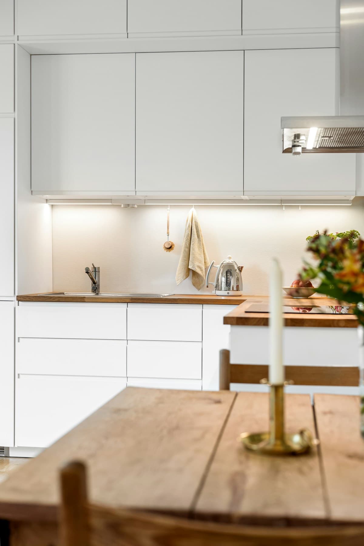 White cabinets and a wood table in a compact kitchen
